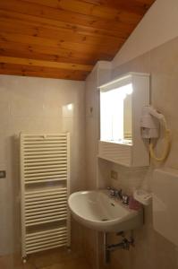 een badkamer met een wastafel, een spiegel en een raam bij Campodolcino Camping in Campodolcino