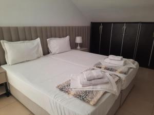 - un grand lit blanc avec des serviettes dans l'établissement Guesthouse "PELIVANI", à Berat