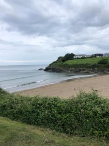 uma praia de areia junto ao oceano num dia nublado em Whispering Creek em New Quay