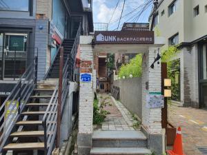 Une allée avec des escaliers et un panneau dans un bâtiment dans l'établissement Bunk Backpackers Guesthouse, à Séoul