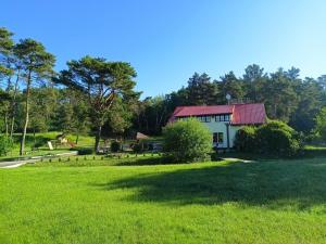 a house with a red roof in a green field at Oberża KNIEJÓWKA in Załom
