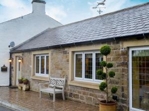 a stone house with a bench in front of it at Collingwood Cottage in Brampton