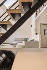 a living room with a couch and a staircase at Schitterende loft met jacuzzi en sauna in Mechelen in Mechelen