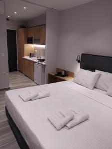 1 dormitorio con 1 cama blanca y 2 toallas en Flâneur apartments, en Ormos Panagias