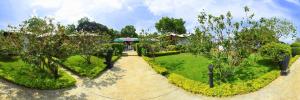 a garden with a pathway and trees and a house at Flower Garden Lake Resort in Tissamaharama