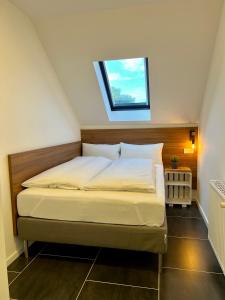 Łóżko w małym pokoju z oknem w obiekcie JUNIPRO Apartments & Rooms w mieście Nohfelden