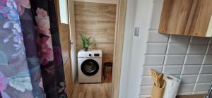 a washing machine in a room with a plant on the door at Lake Room Ełk in Ełk