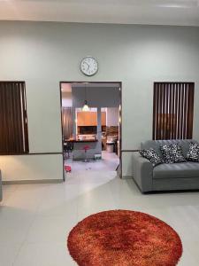 a living room with a couch and a clock on the wall at Villa Syamsu in Bukittinggi