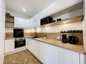 a kitchen with white cabinets and black appliances at AppartChic - appartement standing - plein Centre & Parking privé in Créon