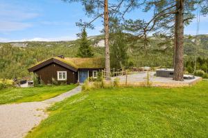 a small house with a grass roof on top of a yard at Libeli- panoramaview towards Gaustadtoppen- Jacuzzi in Lona