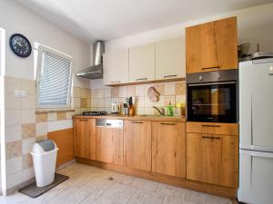 a kitchen with wooden cabinets and a refrigerator at Apartments Jaklin in Rab
