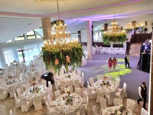 a banquet hall with white tables and chairs and chandeliers at VILA Restaurant Transilvania in Zărneşti