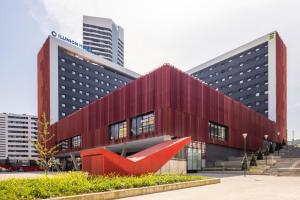 un edificio rojo con una escultura roja delante de él en Hotel Ilunion San Mamés en Bilbao