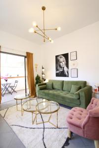 - un salon avec un canapé vert et 2 tables dans l'établissement Design & Balcony in City Center by FeelHome, à Tel Aviv