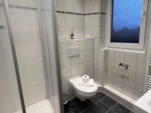 La salle de bains blanche est pourvue de toilettes et d'une fenêtre. dans l'établissement Ferienwohnung Brandung - Haus Seeschwalbe, à Schillig