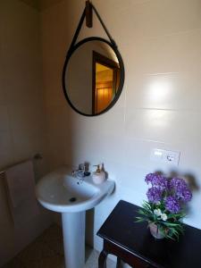 een badkamer met een wastafel, een spiegel en paarse bloemen bij ACASADOCRUCEIRO 