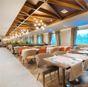 Hotel Rajska dolina Jahorina في ياهورينا: غرفة طعام مع طاولات وكراسي ونوافذ