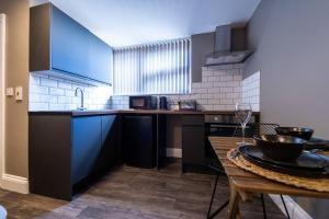 a kitchen with blue cabinets and a wooden table at Veyron Apartments - part of the V Group in Blackpool