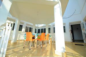 ein Esszimmer mit orangefarbenen Stühlen und einem Tisch in der Unterkunft Ambassador Bridge Motel in Jinja