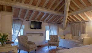 uma sala de estar com um sofá e cadeiras e uma televisão em Villa Morneto em Vignale