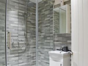 ein Bad mit einer Dusche, einem Waschbecken und einem Spiegel in der Unterkunft Bridge House in Loftus