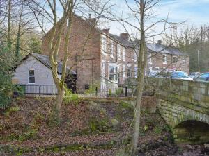 a brick house with a stone bridge and trees at Bridge House in Loftus