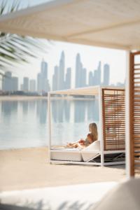 a woman sitting on a bench in front of a large body of water at Raffles The Palm in Dubai
