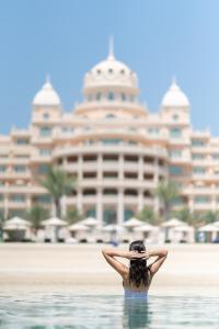 a woman standing in front of a large white building at Raffles The Palm in Dubai