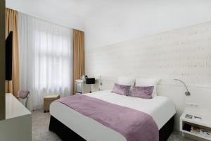 a bedroom with a large bed with purple pillows at Hotel Nemzeti Budapest - MGallery in Budapest