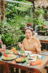 kobieta siedząca przy stole z talerzami jedzenia w obiekcie Nua Tone Resort Bang Tao & Cafe w mieście Bang Tao Beach
