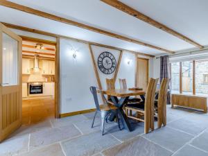 a dining room with a table and chairs and a clock on the wall at Barn View in Clay Cross