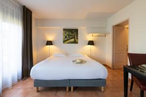 Schlafzimmer mit einem weißen Bett und einem Schreibtisch in der Unterkunft Cerise Carcassonne Sud in Carcassonne