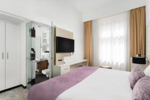 a bedroom with a large bed and a tv at Hotel Nemzeti Budapest - MGallery in Budapest