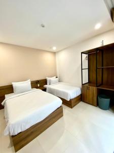 a hotel room with two beds and a cabinet at Bông Villa Hotel & Apartment in Kon Tum
