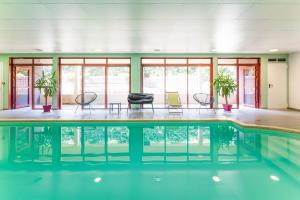 a swimming pool with chairs and tables in a building at Cerise Carcassonne Sud in Carcassonne