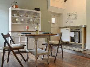 Beck View Cottage في ستيثيس: مطبخ مع طاولة مع كراسي وزجاجة من النبيذ