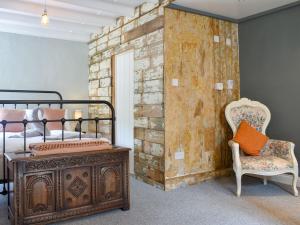 um quarto com uma parede de tijolos, uma cama e uma cadeira. em Beck View Cottage em Staithes