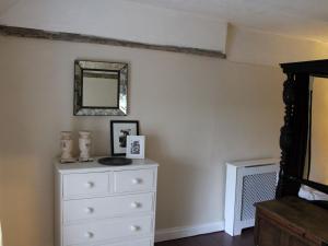 een slaapkamer met een witte dressoir en een spiegel bij Lavender Cottage in Methwold