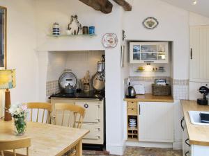 Lavender Cottage في Methwold: مطبخ مع دواليب بيضاء وطاولة