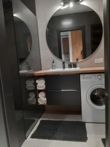 a bathroom with a washing machine and a mirror at Apartament nad Wilgą in Garwolin