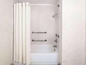 a bath tub with a shower curtain in a bathroom at Days Inn & Suites by Wyndham Opelousas in Opelousas