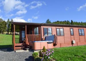 a tiny house with a large porch and a deck at Clear Sky Lodge Park in Falstone