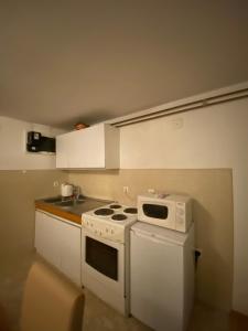 uma pequena cozinha com fogão e micro-ondas em Apartman Benjamin em Tuzla