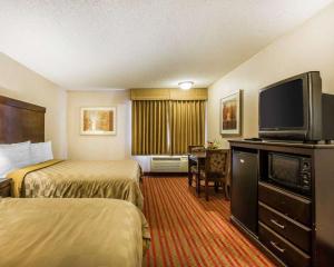 a hotel room with two beds and a flat screen tv at California Inn and Suites Bakersfield in Bakersfield