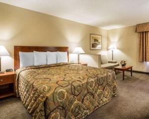 a hotel room with a large bed and a chair at California Inn and Suites Bakersfield in Bakersfield