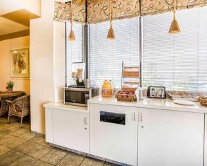 a kitchen with white cabinets and a microwave at California Inn and Suites Bakersfield in Bakersfield