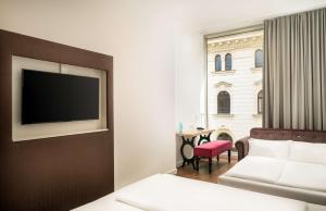 a hotel room with a couch and a television on a wall at Arthotel Ana Symphonie in Leipzig