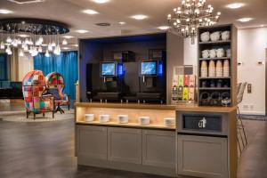 a coffee shop with a counter and chandeliers at elaya hotel leipzig city center in Leipzig