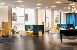 a lobby with couches and a piano in a building at elaya hotel leipzig city center in Leipzig