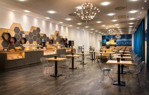 a restaurant with tables and chairs and a counter at elaya hotel leipzig city center in Leipzig